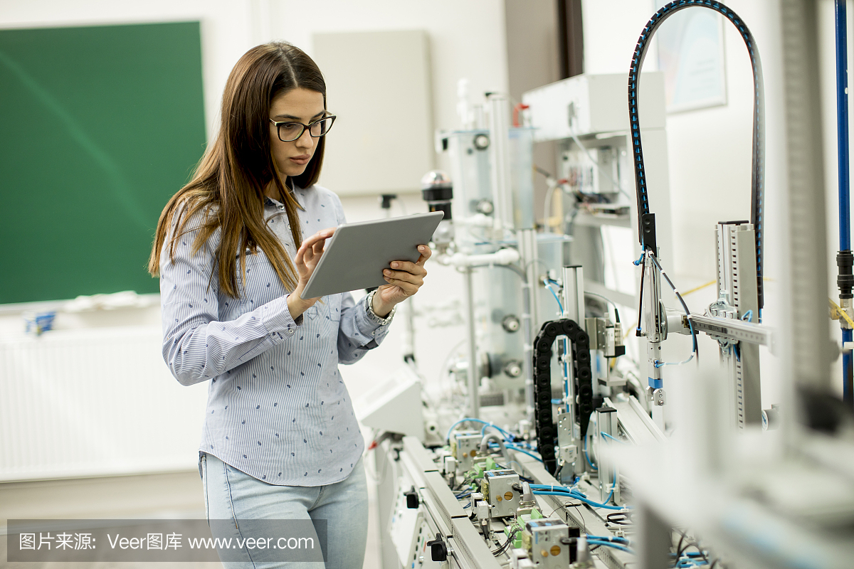 年輕女子在電子車(chē)間拿著平板電腦